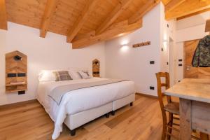 a bedroom with a white bed and a wooden floor at B&B El Lares - B&B L'Avez in Canale dʼAgordo