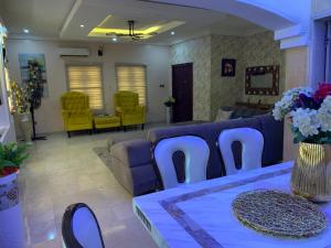 a living room with a blue couch and yellow chairs at Charming Vacation 3BDR Duplex - Free Wi-Fi, Washing Machine, Mins to Airport in Agege