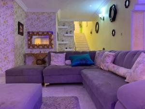 a living room with a purple couch and a fireplace at Charming Vacation 3BDR Duplex - Free Wi-Fi, Washing Machine, Mins to Airport in Agege