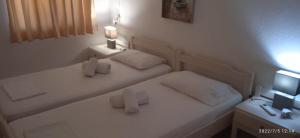 a white bedroom with two beds and a television at lemonishouse by the sea 2 in Nea Skioni
