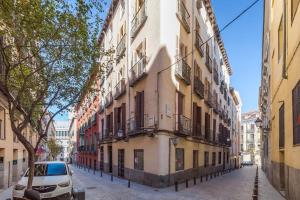 un edificio en una calle con un coche aparcado al lado en Luminoso y amplio apartamento en Ópera, en Madrid