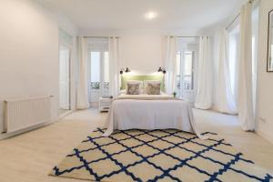 a white bedroom with a large bed and a rug at Luminoso y amplio apartamento en Ópera in Madrid