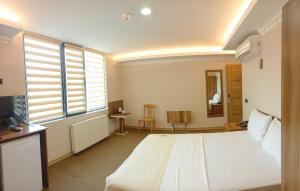 a bedroom with a large white bed and a television at Osmanlı Paşa Otel- Konaklama in Samsun