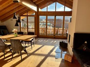 ein Esszimmer mit einem Tisch, Stühlen und Fenstern in der Unterkunft Wally Luxus Lodge im Ferienhaus Magdalena in Mittenwald