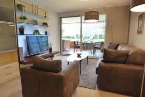 un soggiorno con divano, TV e tavolo di Appartement am See mit Pool und Sauna a Melide