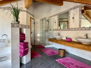 La salle de bains est pourvue de 2 lavabos, de 2 miroirs et de tapis roses. dans l'établissement Wally Luxus Lodge im Ferienhaus Magdalena, à Mittenwald