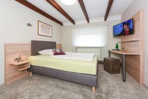 a bedroom with a bed and a tv on the wall at Pension Nordlicht in Esens