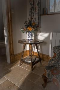 a vase of flowers on a table in a room at The Rear of the Plough,Everdon. in Daventry