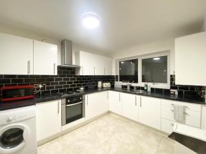 a kitchen with white cabinets and a washer and dryer at ThePropertyFocus - Stylish Cosy Stay in Manchester