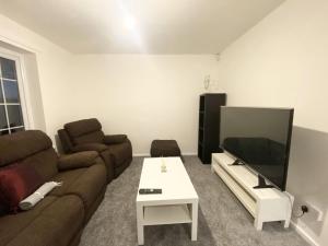 a living room with a couch and a flat screen tv at ThePropertyFocus - Stylish Cosy Stay in Manchester