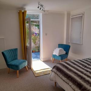 a bedroom with two blue chairs and a bed at The Hideaway in Swanage
