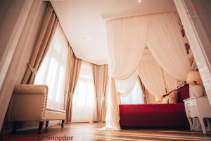a bedroom with a canopy bed with curtains and a chair at Vili Apartments in Oradea