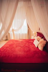 a red bed with curtains and two teddy bears on it at Vili Apartments in Oradea +140 photos