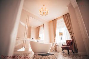 a living room with a white chair and a chandelier at Vili Apartments in Oradea