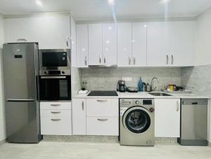 a kitchen with white cabinets and a washing machine at Apartamento adosado con terraza en Playa América, Nigrán in Nigrán +8 photos
