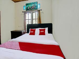 ein Schlafzimmer mit einem Bett mit zwei roten Kissen in der Unterkunft OYO 92059 Archi Homestay in Lembuak