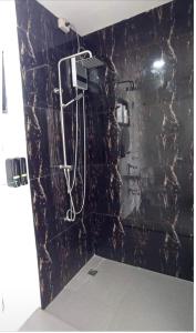 La salle de bains est pourvue d'une douche et d'un mur en marbre noir. dans l'établissement The Nova Scotia Resort Botolan, à Binuclutan
