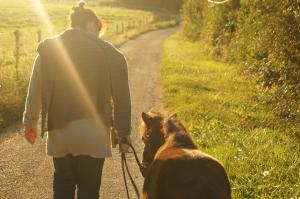 a woman walking a dog on a dirt road at Gite de la Jument grise-calme et tranquillité in Lescheroux