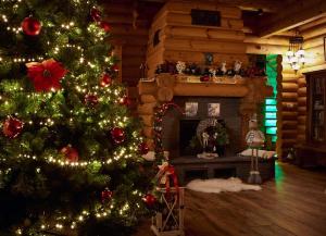 a christmas tree in a living room with a fireplace at Greenwood Rönkház in Gárdony