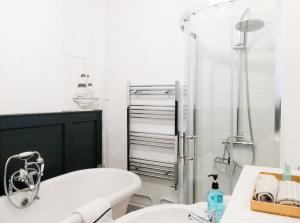 a white bathroom with a tub and a shower at Ye Olde Smugglers Inne in Alfriston