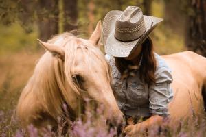 Una donna con un cappello da cowboy che cavalca un cavallo di Pferdeparadies Calm River Ranch a Wedemark