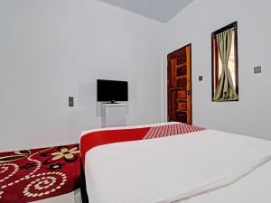 a white bedroom with a bed and a television at OYO 92054 Gala Residence in Jambi