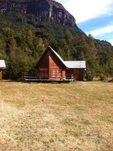 a barn in a field with a mountain in the background at Cabaña Arriendo Llifen in Futrono