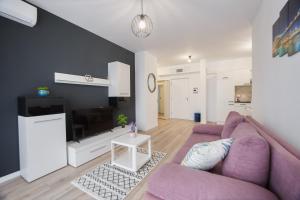 a living room with a purple couch and a tv at Duet Noir in Oradea