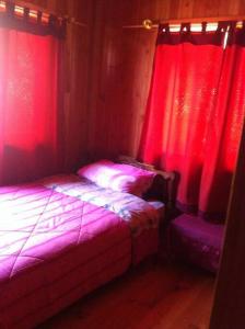 a bedroom with two beds and red curtains at Cabaña Arriendo Llifen in Futrono