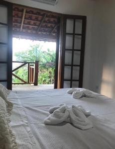 Una cama blanca con toallas y una ventana. en Pousada Cantinho D'Abrantes - Próximo as Melhores Praias de Ilhabela - Veloso e Curral, en Ilhabela