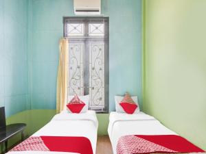 two beds in a room with a window at OYO 92055 Nirvana Homestay Syariah in Bangkinang