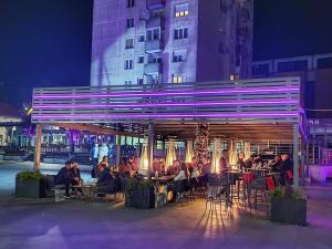 a group of people sitting at tables in front of a building at Apartman City in Livno