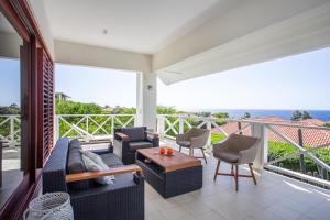 d'un salon avec un canapé et des chaises sur un balcon. dans l'établissement Boca Gentil sea view apartment - Jan Thiel, à Jan Thiel