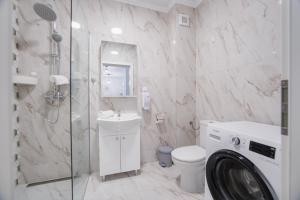 une salle de bain avec toilettes et lavabo et une machine à laver dans l'établissement Duet Blanc, à Oradea