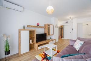 un salon avec un canapé violet et une télévision dans l'établissement Duet Blanc, à Oradea