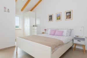 1 dormitorio blanco con 1 cama blanca grande con almohadas rosas en Studio LAVANDA - Explore Istrian Riviera and Inland en Tinjan