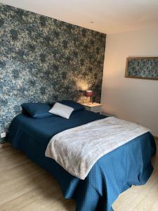 ein Schlafzimmer mit einem blauen Bett mit einer blumengeschmückten Wand in der Unterkunft LES GLYCINES in Hières-sur-Amby