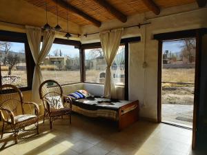 Habitación con cama, sillas y ventanas. en CabañaPerchel Tilcara Quebrada de Humahuaca en Huacalera