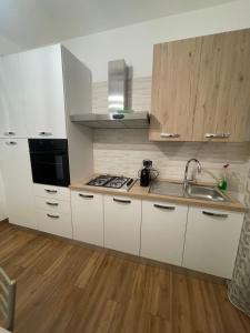 una cucina con armadi bianchi e lavandino di Prestige Appartament a Casale Monferrato
