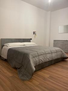 un grande letto in una camera bianca con pavimenti in legno di Prestige Appartament a Casale Monferrato