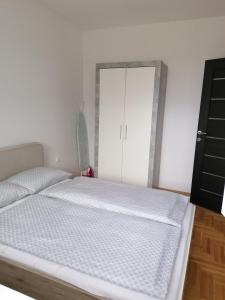 - une chambre avec un lit blanc et un miroir dans l'établissement Northern Pearl, à Subotica