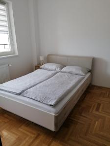 - un lit blanc dans une chambre dotée de parquet dans l'établissement Northern Pearl, à Subotica