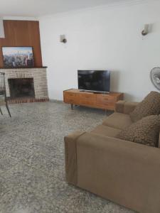 sala de estar con sofá y TV de pantalla plana en ALQUILER DE CASA POR TEMPORADA en Necochea