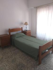 Un dormitorio con una cama verde y una ventana en ALQUILER DE CASA POR TEMPORADA en Necochea