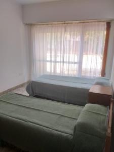 1 dormitorio con 2 camas y ventana en ALQUILER DE CASA POR TEMPORADA en Necochea