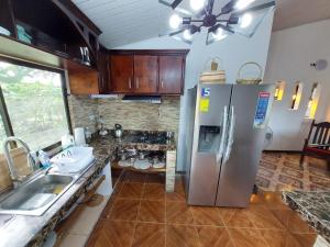 a kitchen with a stainless steel refrigerator and a sink at Private Mountain House With a Pool in Orotina