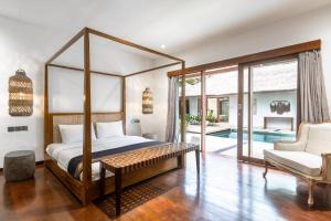 a bedroom with a canopy bed and a swimming pool at Villa Lima Hati in Kerobokan