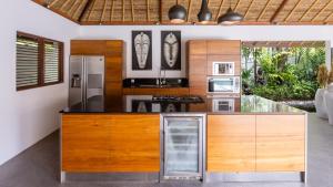 an open kitchen with wooden cabinets and stainless steel appliances at Villa Lima Hati in Kerobokan