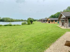 a large grassy field next to a row of houses at Lake Pochard, Oak Lodge in South Cerney