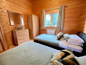 um quarto com 2 camas num chalé de madeira em Lake Pochard, Oak Lodge em South Cerney